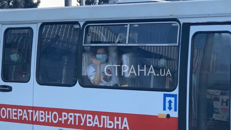 Эвакуированная из Китая пассажирка машет рукой журналистам и харьковчанам
