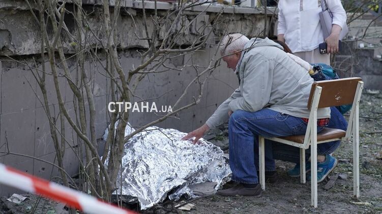 Погибшая в Киеве девочка и ее дедушка, который сидит у тела ребенка. Фото 