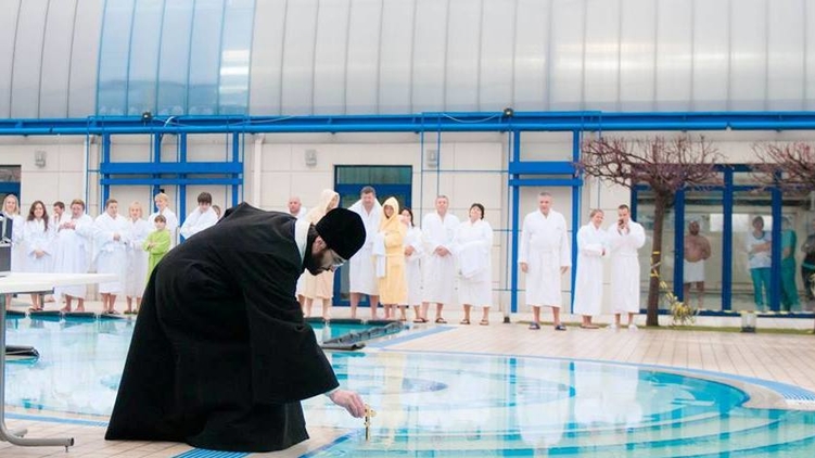 Батюшка святит воду в открытом бассейне клуба 