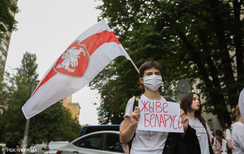 участник акции протеста в Киеве в флагом Беларуси